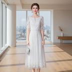 Woman wearing a white lace dress against a gray background